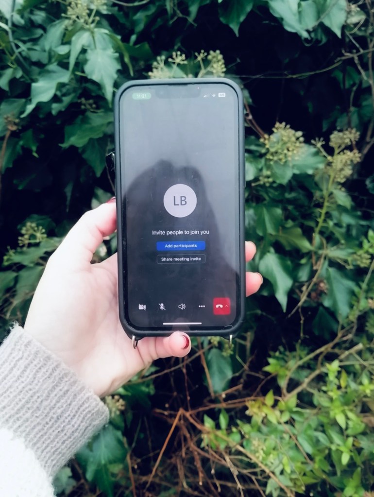 An image of a hand holding a mobile phone outdoors in a remote counselling session 